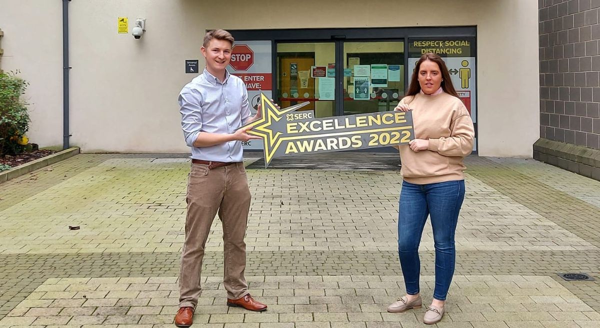 Michael Holmes and Gemma Diamond hold the Excellence Awards Logo